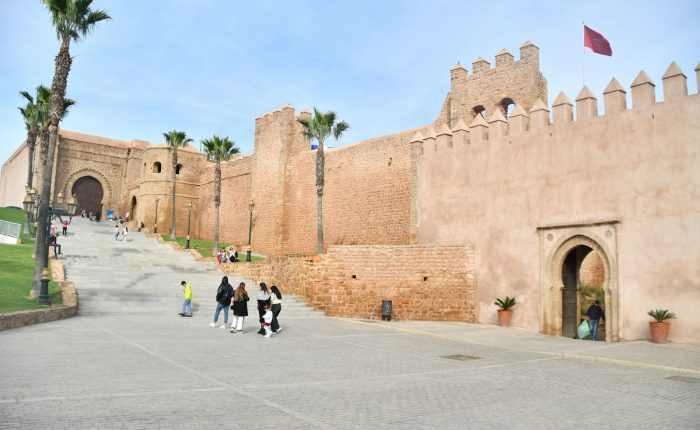 a group of people walking down a street next to a castle