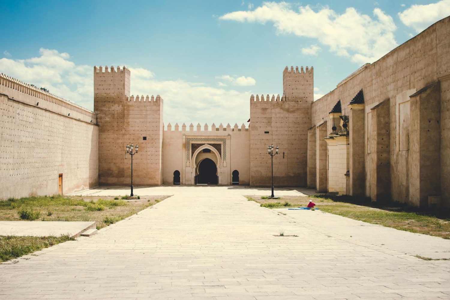 A grand fortress with towering walls and a central archway under a blue sky.
