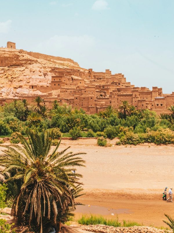 people walking on brown sand near brown rock formation during daytime