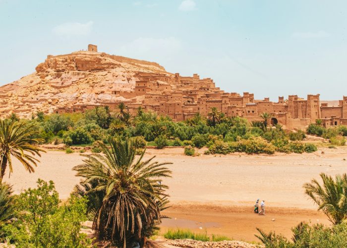 people walking on brown sand near brown rock formation during daytime